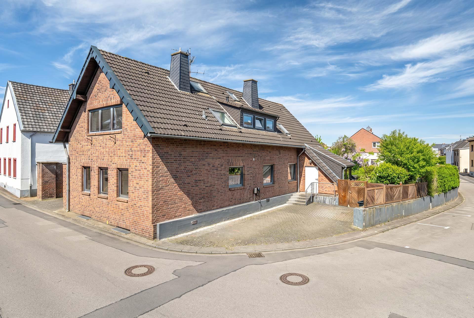 Seitenansicht des Dreifamilienhauses mit der Wallbox und den Stellplätzen für Wohnung #1 und Wohnung #2. Immobilie Bedburg