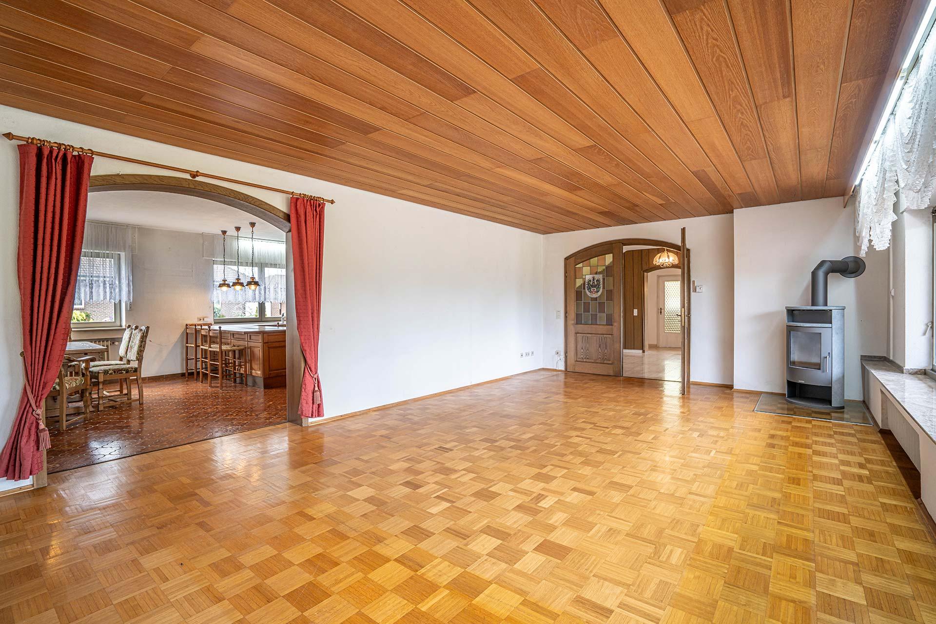 Das Wohnzimmer im Erdgeschoss mit Rundbogen und Flügeltür in die Diele, offenem Rundbogen in die Wohnküche und Kamin Immobilie Bedburg