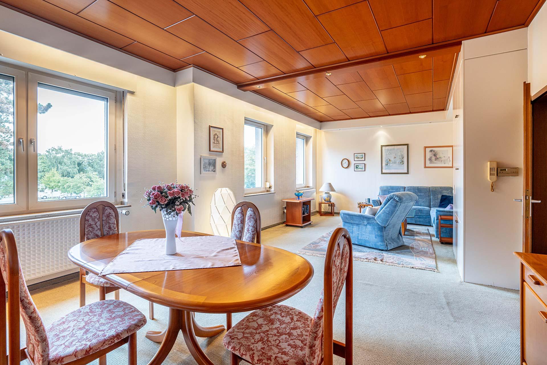Das Wohn und Esszimmer im Obergeschoss aus der Ecke hinter dem Esstisch fotografiert. Man ergennt die großen Fenster zur Vorderseite und wie viel Platz in diesem Raum ist. Immobilie Bedburg