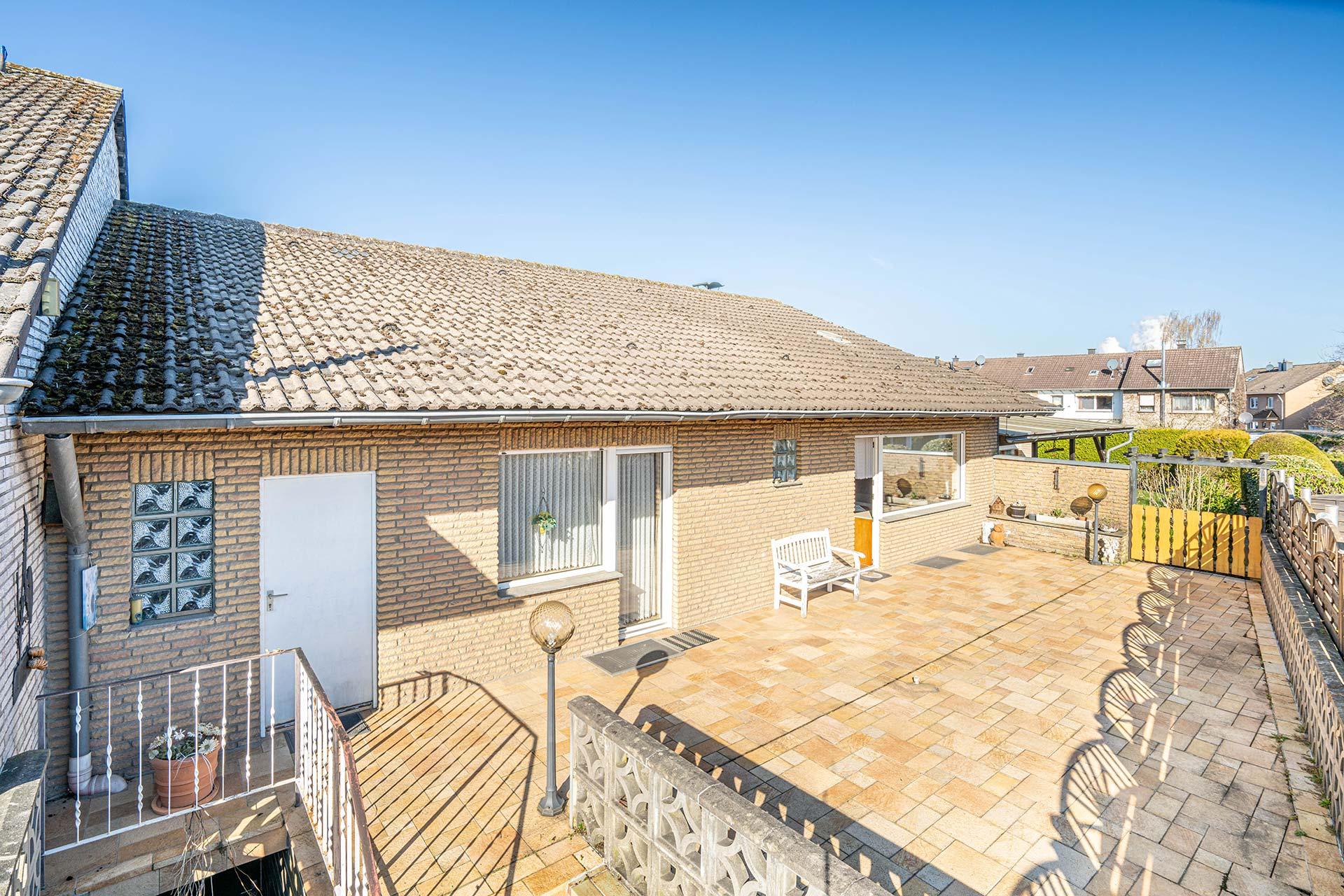 Die Rückansicht der Immobilie mit Kelleraußentreppe, Zugang zum Werstattraum hinter der Garage und zu Schlafzimmer und Wohnzimmer. Bungalow Bergheim