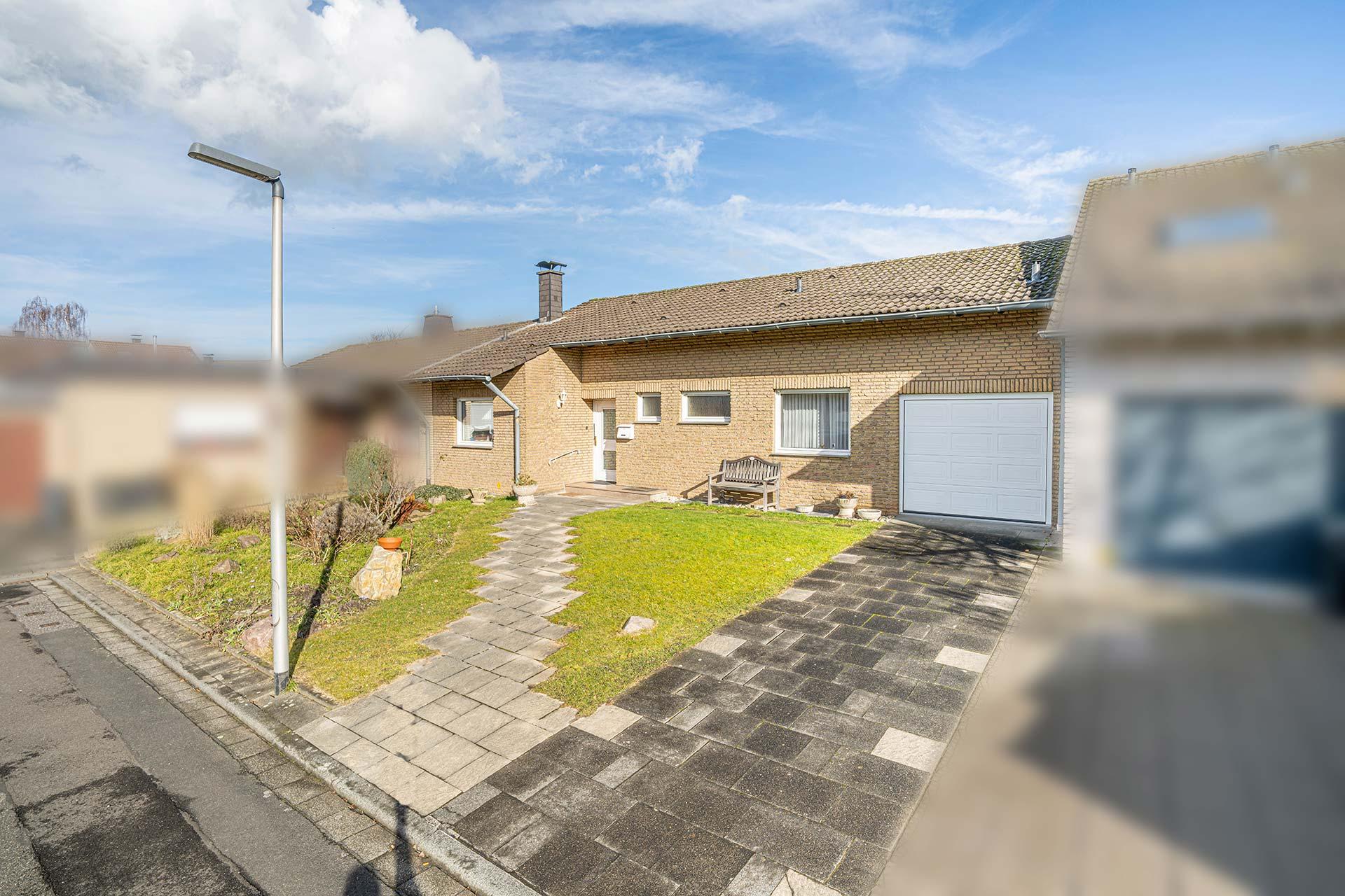 Vorderansicht der Immobilie bei eEinfahrt in die Sackgasse. Im Vordergrund liegt die Zufahrt zur integrierten Garage. Bungalow Bergheim