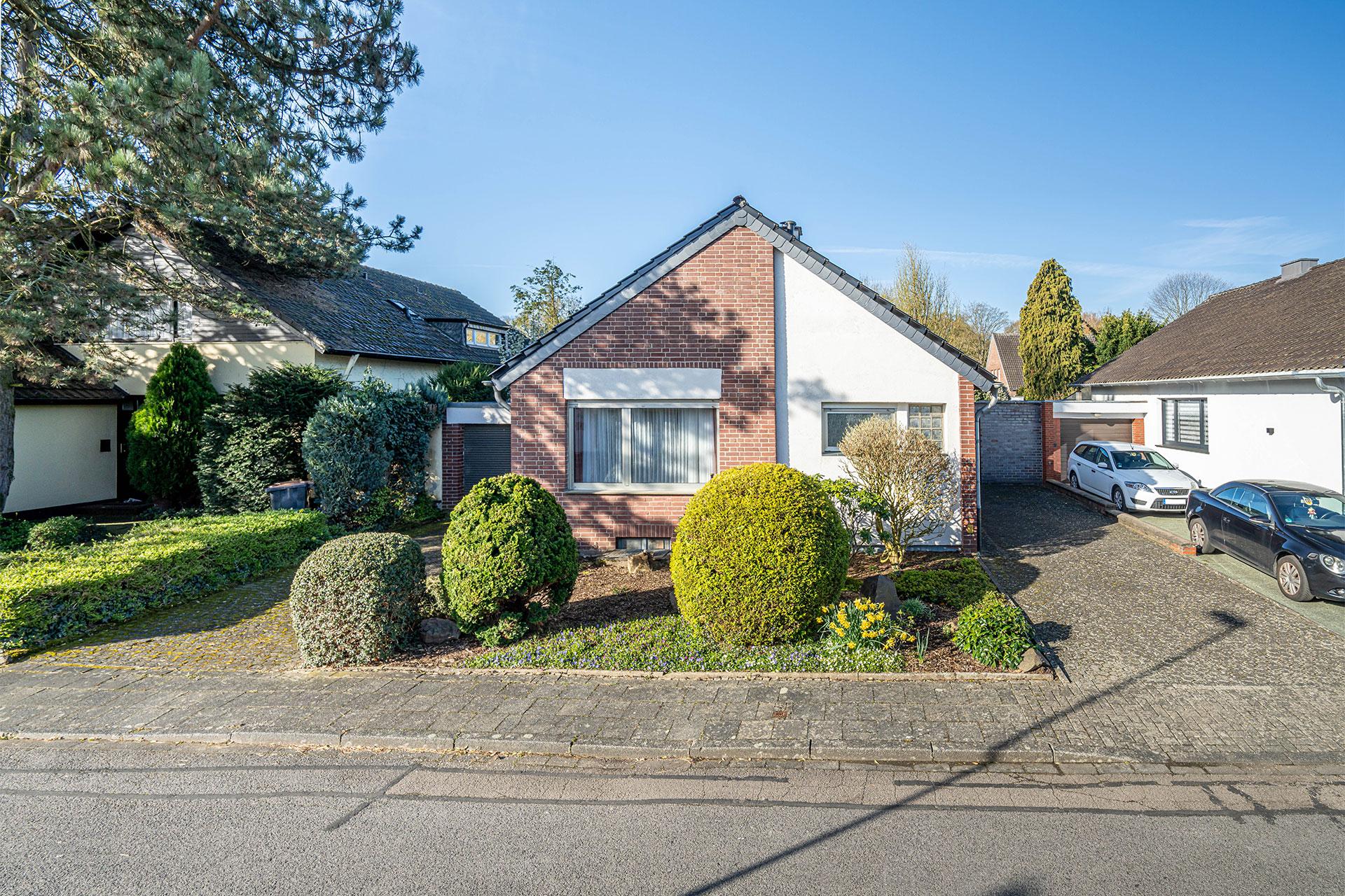 Vorderansicht Einfamilienhaus mit Blick auf die Garage links und den Stellplatz mit Hauseingang recht vom Haus Bungalow Kerpen