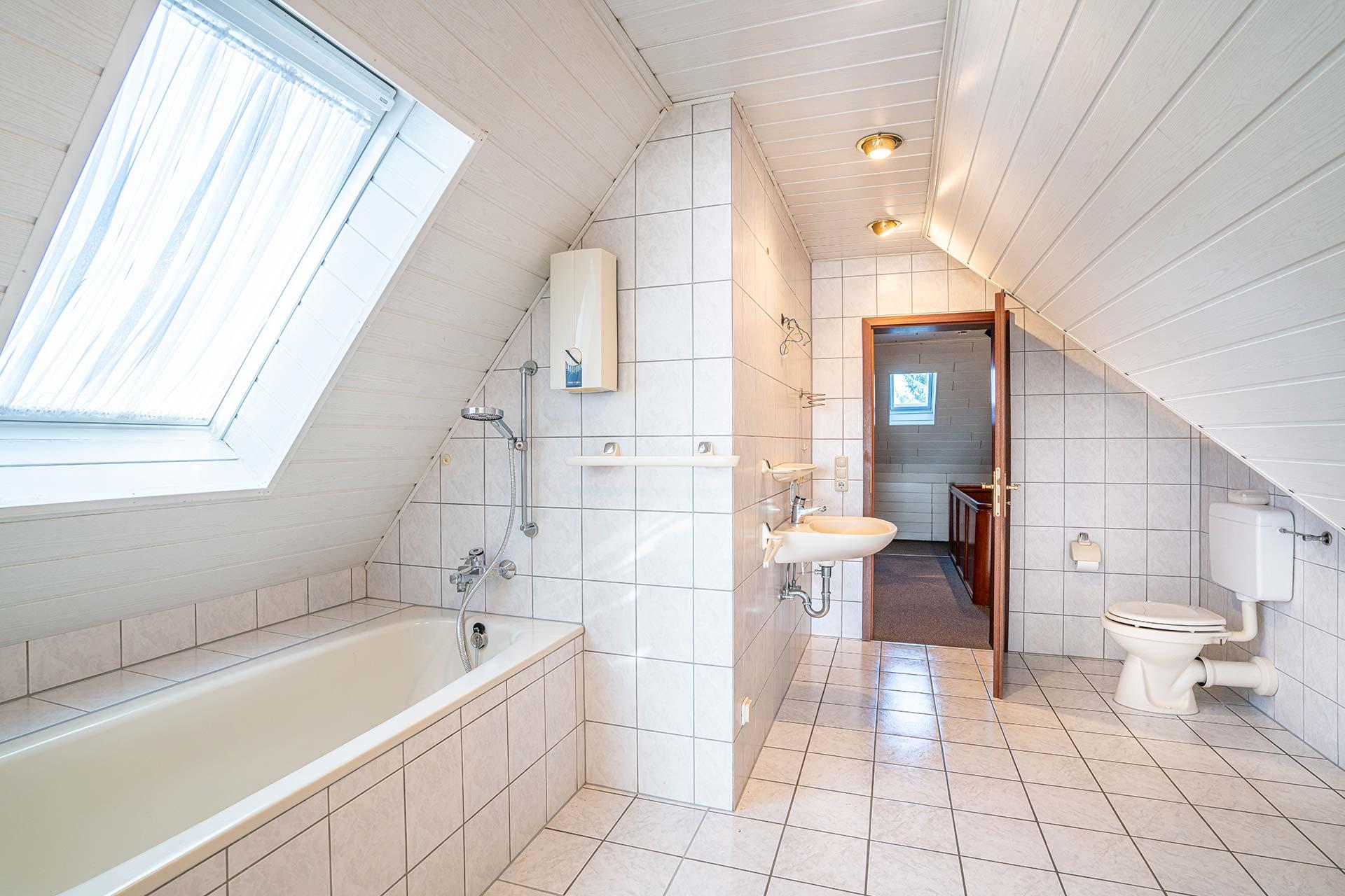Das Wannenbad im Dachgeschoss ist mit einem Dachflächenfenster, einer Badewanne, einem Stand-WC und einerm Waschbecken ausgestattet. Es ist zugleich der Durchgang zum Büro. Doppelhaushälfte Bergheim