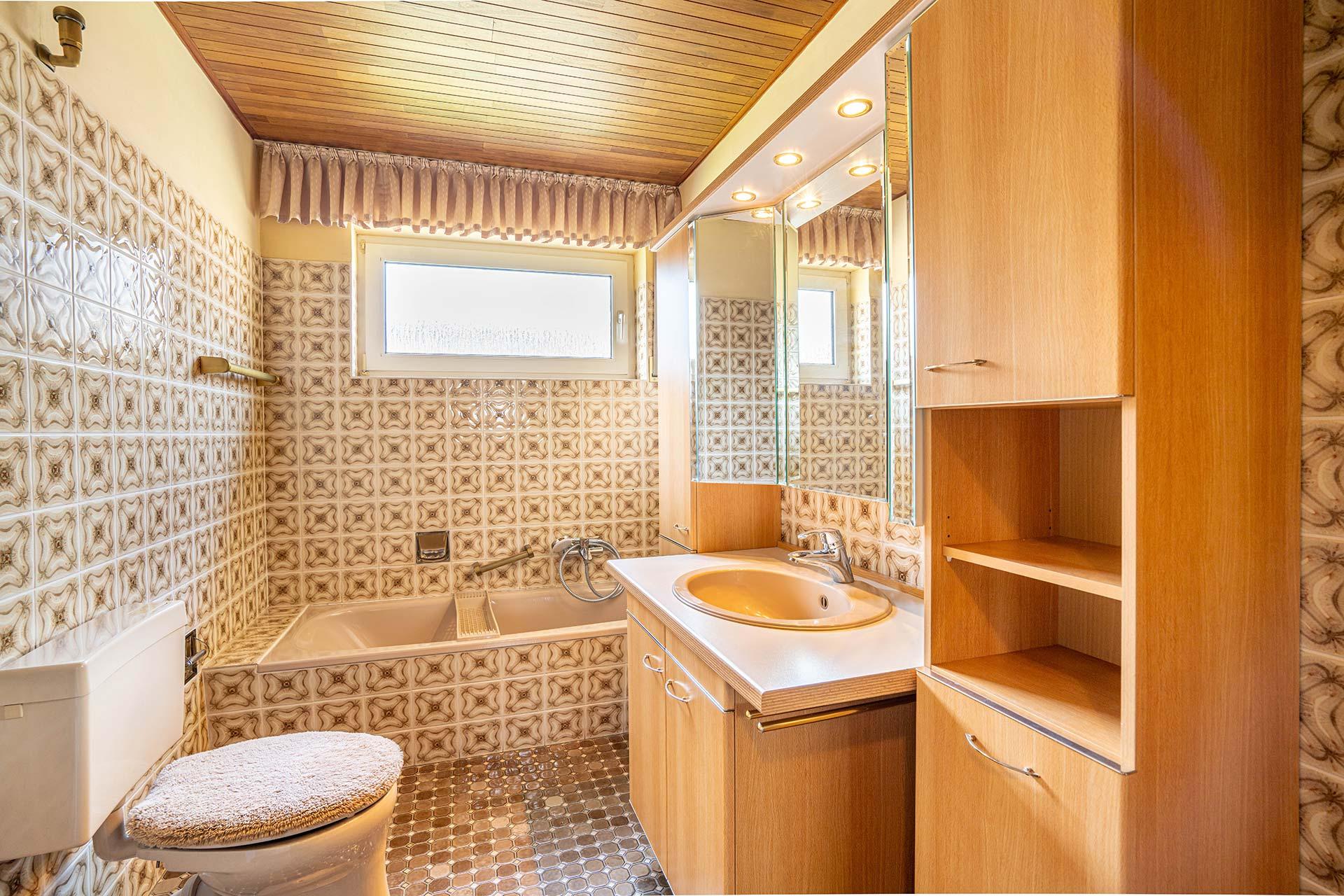 Das Wannenbad im Erdgeschoss mit Badewanne, Tageslicht durch ein Fenster, Waschtisch und Stand-WC. Bungalow Bergheim